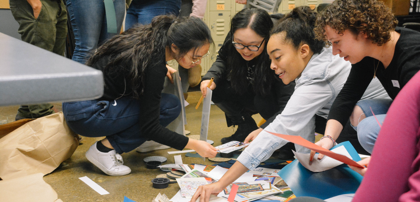 Four female U-M students look through printed materials.